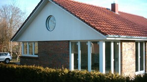 A single-story house with a red-tiled roof, a brick facade, and a large circular window. - Kajüte Vacation Home - - Kajüte Vacation Home - (Brodersby)