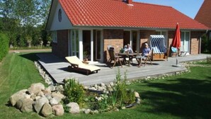 A house with a red roof, a covered patio, and a lawn. - Kajüte Vacation Home - - Kajüte Vacation Home - (Brodersby)