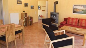 A living room with a fireplace, wooden furniture, and a red sofa. - Kajüte Vacation Home - - Kajüte Vacation Home - (Brodersby)