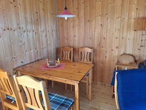 A wooden dining area with a table, chairs, and a small table with a candle arrangement.
