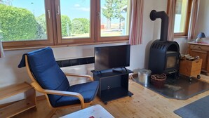 En stue med tv, en blå stol, pejs og udsigt til det fri.
