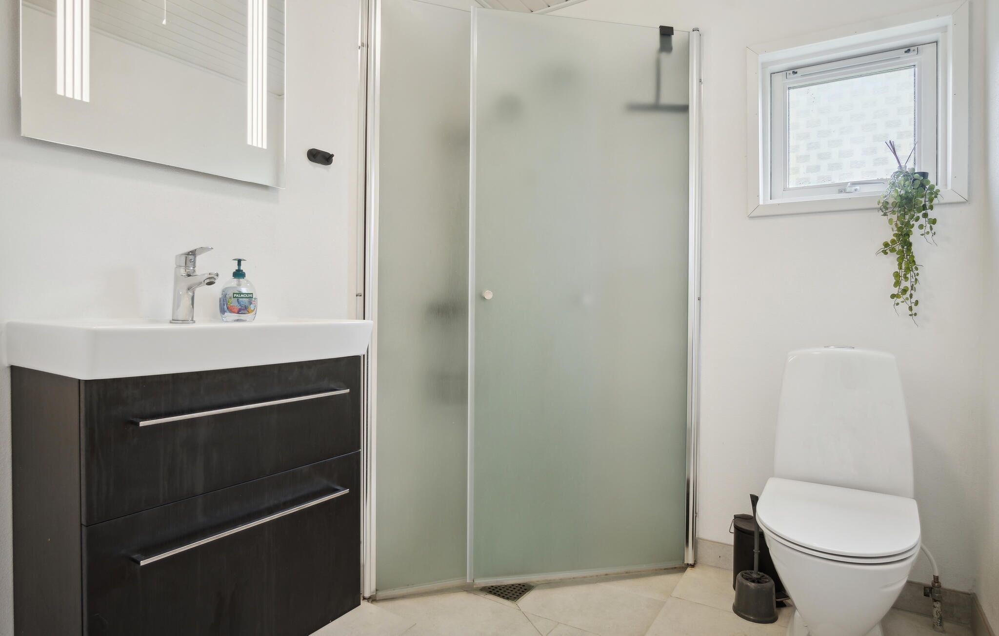 A modern bathroom with a shower enclosure, a toilet, and a sink with a mirror above it.