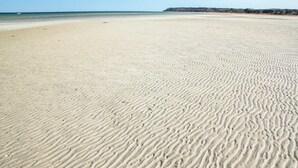 Un'ampia spiaggia di sabbia con onde dolci che si infrangono sulla riva.
