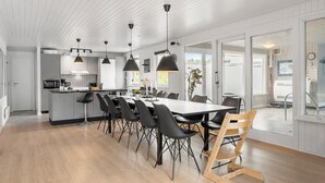Una cucina moderna con isola centrale, sedie nere e illuminazione a sospensione.