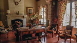 Une pièce de style traditionnel, dotée d’une cheminée, d’un bureau et de plusieurs chaises.