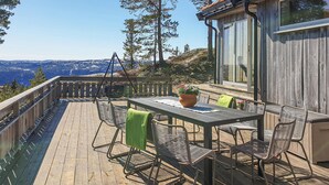 En træterrasse med et bord og stole, med udsigt over et bjergrigt landskab.
