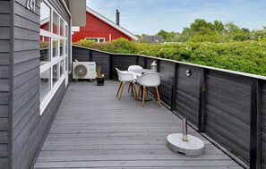 Eine Holzterrasse mit Tisch, Stühlen, einem Ventilator und einem Blumentopf.