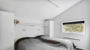 Ett sovrum med en säng, ett fönster med utsikt och inbyggda hyllor.