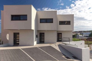 A modern multi-story building with three visible doors and windows.