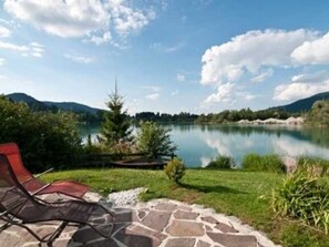 Vista sul lago con patio in pietra e una poltrona reclinabile rossa.