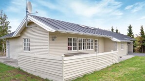 Een gelijkvloers huis met een schuin dak, een schotelantenne en een overdekte veranda.
