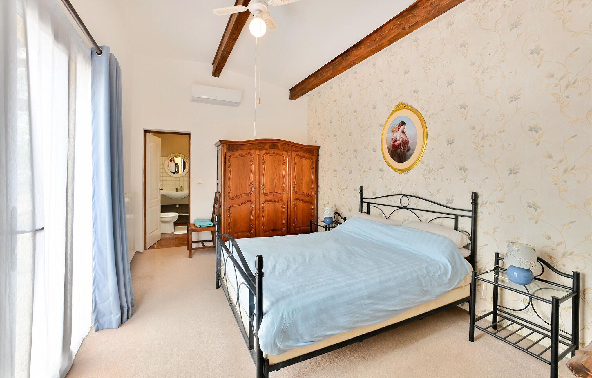 A bedroom with a bed, a wardrobe, a mirror, and a ceiling fan.