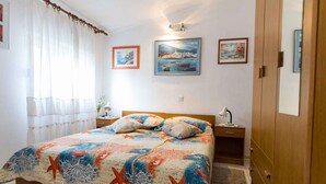 Ein Schlafzimmer mit Bett, Nachttischen, einem Holzschrank und Wandbildern.
