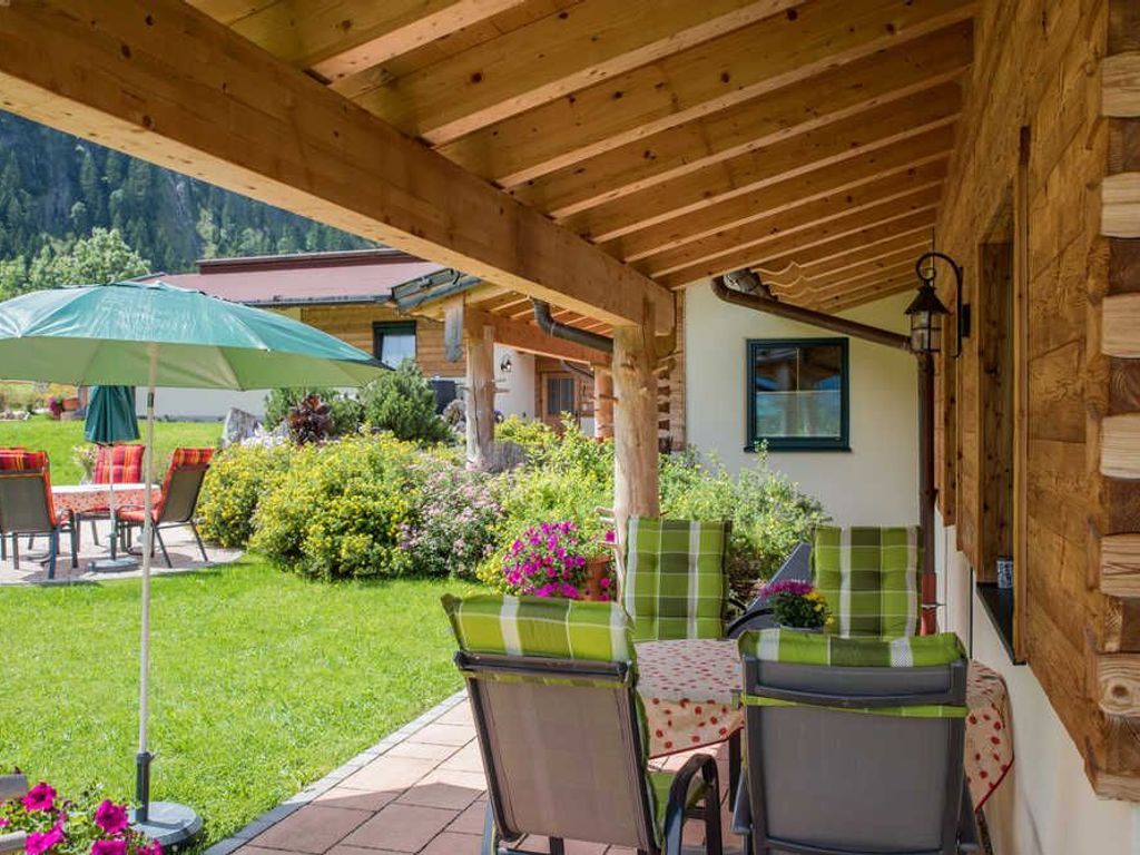 A covered patio with outdoor seating, a wooden ceiling, and a view of a mountain.