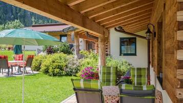 A covered patio with outdoor seating, a wooden ceiling, and a view of a mountain.
