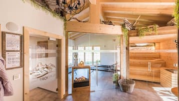 Un interior de madera con zona de sauna, puerta de cristal y vistas al exterior.