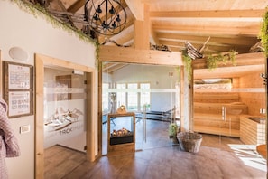 A wooden interior with a sauna area, a glass door entrance, and a view of the outdoors.