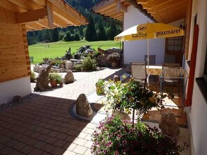 Un patio al aire libre con una sombrilla amarilla, una mesa y vistas a un paisaje verde.