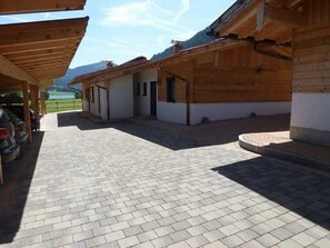 A covered outdoor area with a paved walkway leading to a row of wooden buildings.