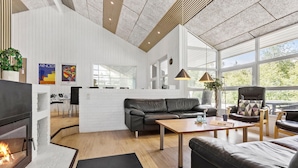 Un salon moderne avec une cheminée, un canapé, une table basse et un coin repas.