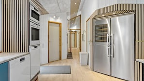 Une cuisine moderne dotée d’un four encastré, d’un réfrigérateur en acier inoxydable et d’un plancher en bois.