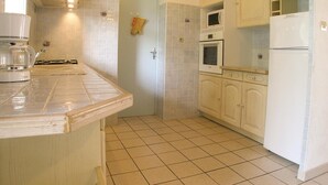 Una cocina con gabinetes blancos, un microondas, un horno y una cafetera.