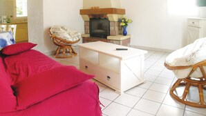 Una habitación acogedora con cama, una silla, una mesita, chimenea y una zona de cocina.