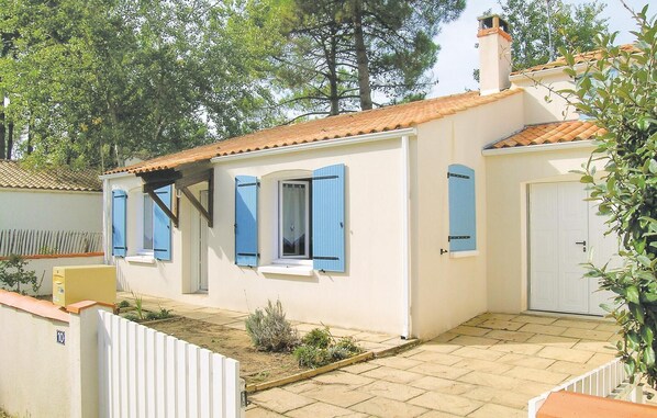 A single-story house with a tiled roof, blue shutters, and a white door. - 3 bedroom awesome home in La Tranche sur Mer (La Tranche sur Mer)