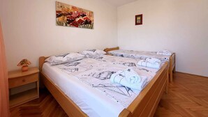 Un lit double avec une couvre-lit sur le thème de la marine, une table de chevet avec une lampe et un tableau de fleurs accroché au mur.