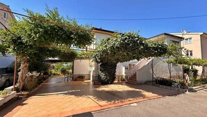 Un quartier résidentiel avec une allée pavée, un patio couvert et un escalier menant à un bâtiment.