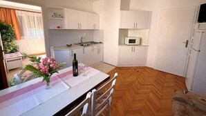 Une cuisine compacte avec des meubles blancs, un four à micro-ondes et un coin repas avec une table dressée pour deux personnes.