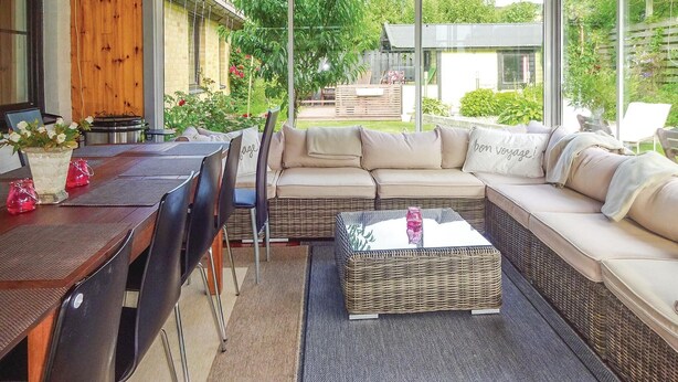 Un espace extérieur aménagé avec un canapé en osier, une table et des chaises.