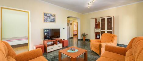 A living room with orange sofas, a TV, and a wooden coffee table.