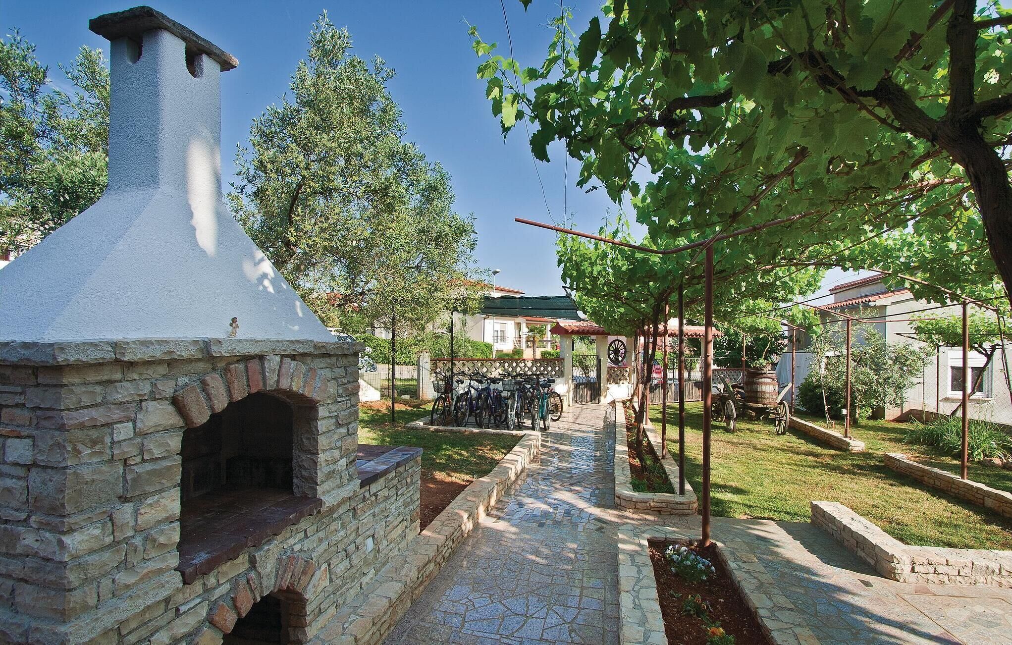 A stone-built outdoor oven, a paved pathway, and a residential area with a house and bicycles.