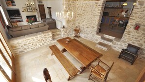 Un vaste espace de vie agrémenté d’un mur en pierre, d’une table à manger en bois, de bancs et d’une cheminée.