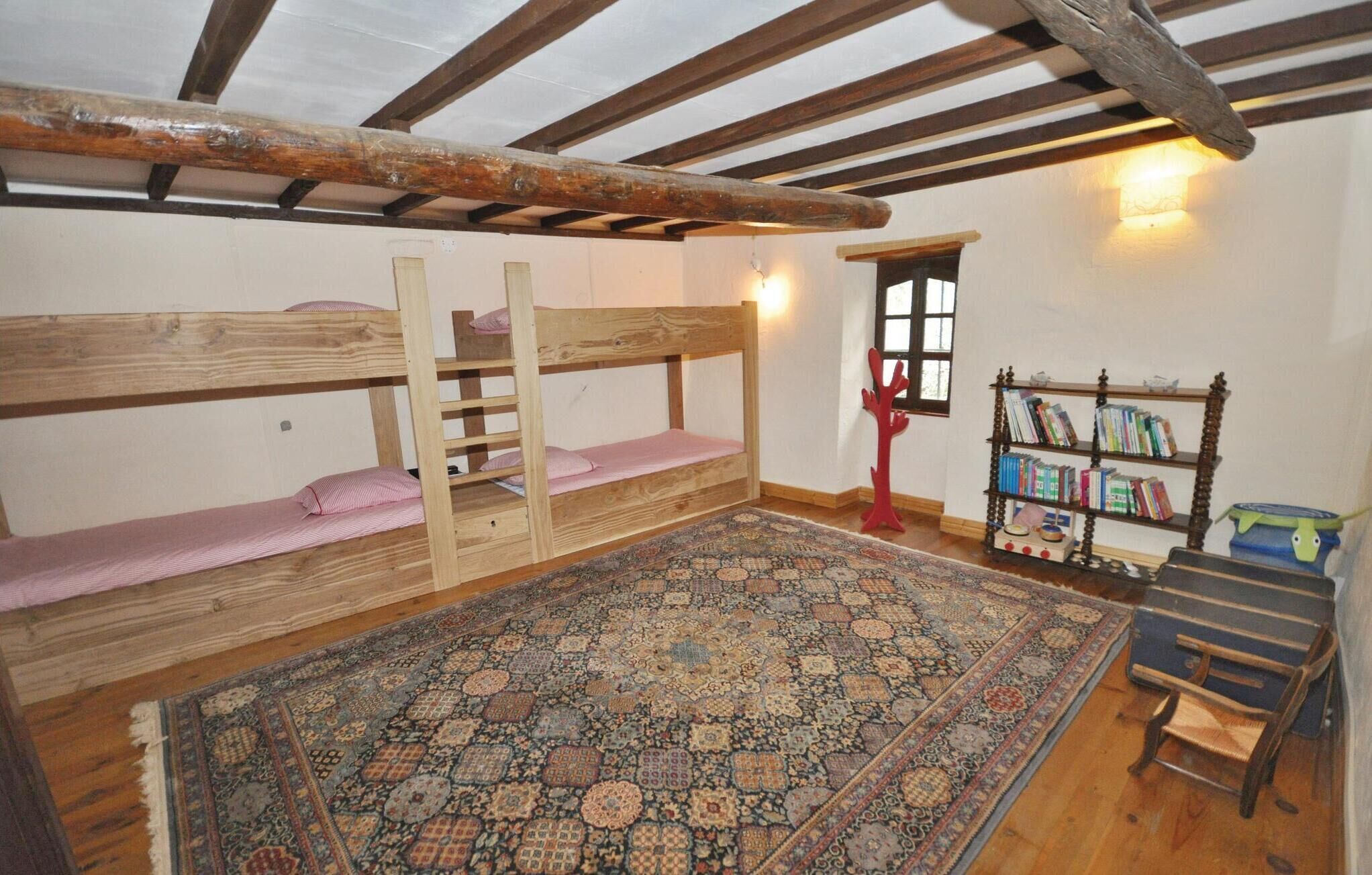 Une chambre avec des lits superposés, un tapis à motifs, une bibliothèque et une fenêtre donnant sur un beau paysage.