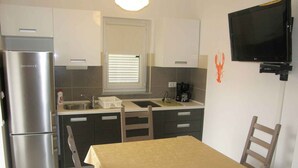 Una cocina compacta con refrigerador, lavamanos y comedor con mesa y sillas.