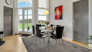 Un coin repas avec une table ronde, des chaises noires, un vase de fleurs et un tableau au mur.