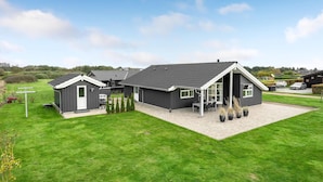 Une maison moderne dotée d’un grand patio, d’un garage séparé et d’une pelouse bien entretenue.