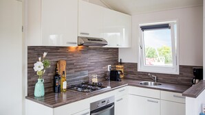 A modern kitchen with white cabinets, a gas stove, a built-in oven, a window with a view, and a wooden backsplash. - Cozy home in Breukelen with WiFi (Breukelen)