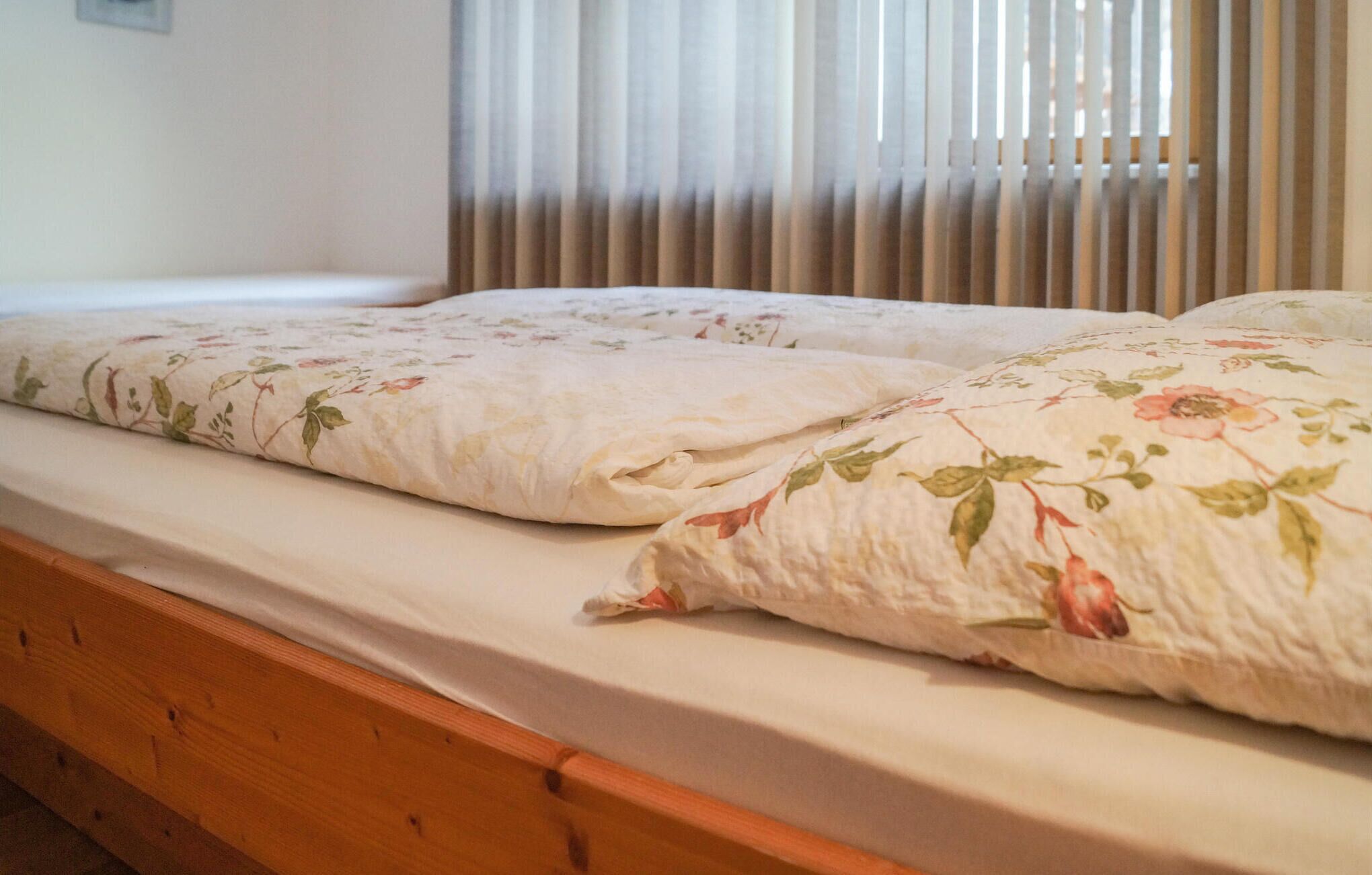 A double bed with floral bedding and a wooden headboard.