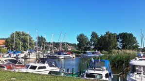 A marina with various boats docked, surrounded by greenery and trees.