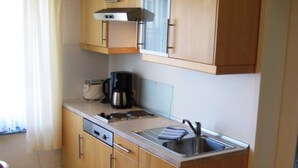 A compact kitchen with wooden cabinets, a stainless steel sink, a coffee maker, and a toaster.