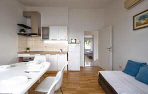 A compact, modern apartment with a kitchenette, a dining area, and a bedroom.