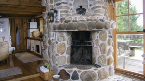 A stone fireplace with a metal screen, surrounded by wooden walls and a wooden ceiling.