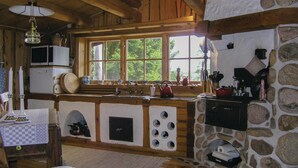 A rustic kitchen with a stone wall, wooden beams, and a large window.