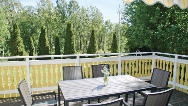 A wooden deck with a white railing, a table, and chairs. - 3 bedroom gorgeous home in Svanesund (Svanesund)