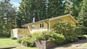 A yellow cabin with a brick foundation, surrounded by dense greenery and tall trees. - 3 bedroom gorgeous home in Svanesund (Svanesund)