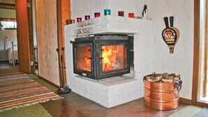 A stone fireplace with a fire, a copper bucket of wood, and a penguin-shaped beer tap on the wall. - 3 bedroom gorgeous home in Svanesund (Svanesund)