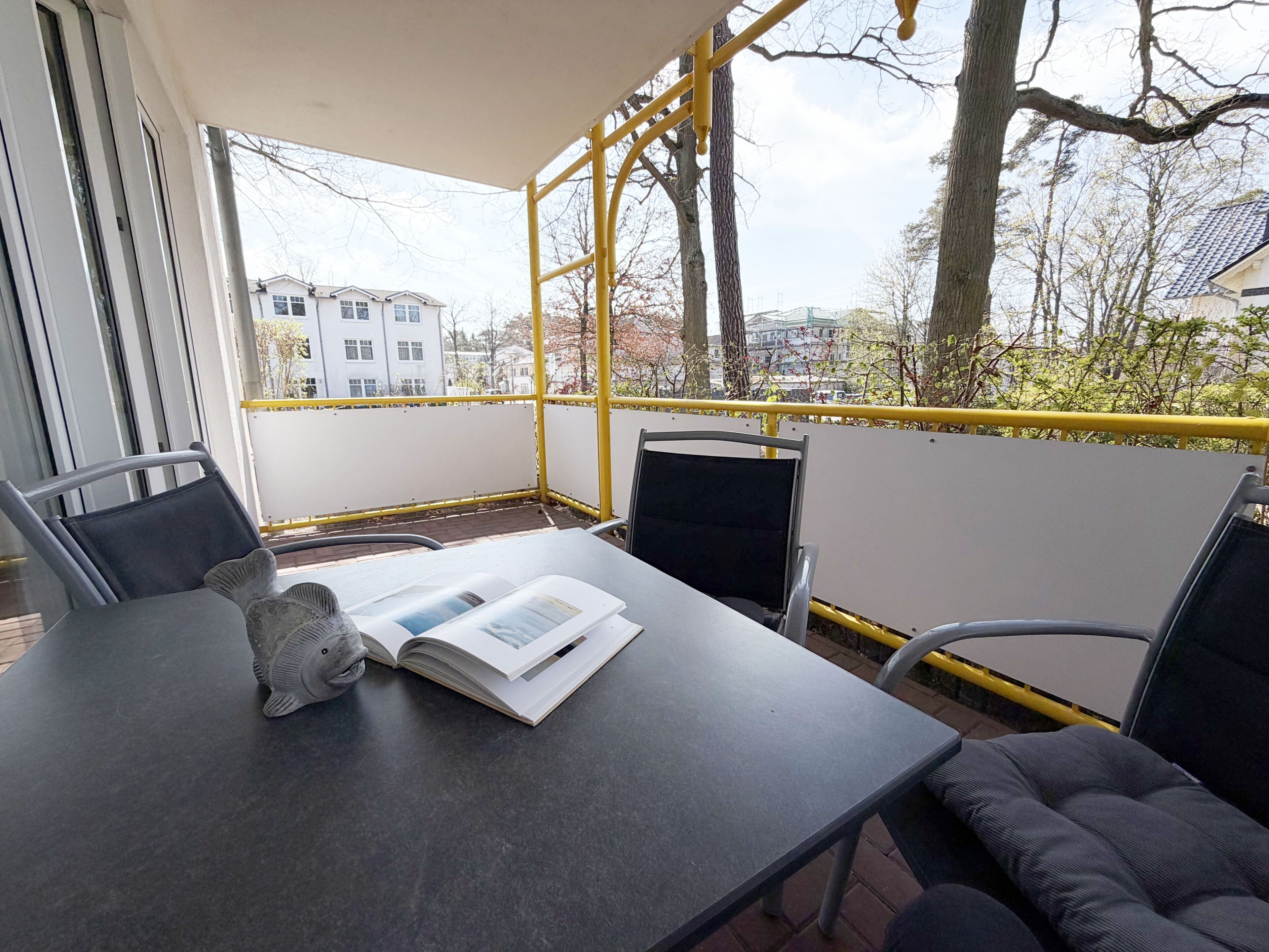 A balcony with a table, chairs, and a book.